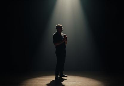 An actor performing a powerful monologue on a small stage with a single spotlight, showing focus and intensity